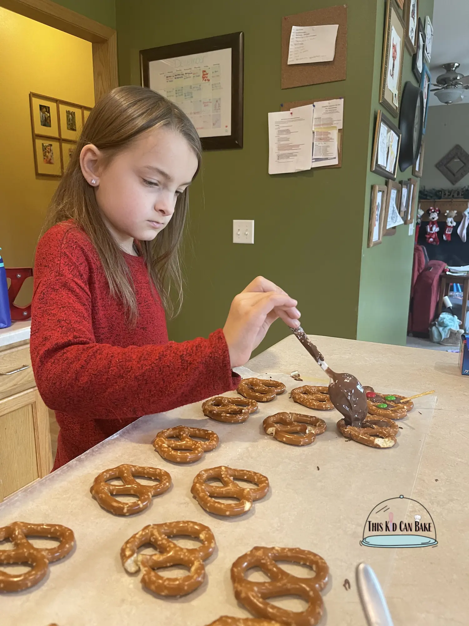 A picture of a child filling pretzels with chocolate to make reindeer chocolate pretzels for Christmas baking.