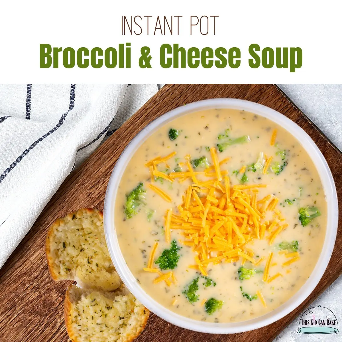 A picture of broccoli and cheese soup in a white bowl on a cutting board with a striped towel and a piece of garlic bread.